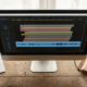 Course localization desk with a monitor showing caption bars and an audio waveform, storyboard sheets and headphones