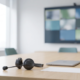 Meeting room with a video-call wall display and a headset with a boom microphone on the desk